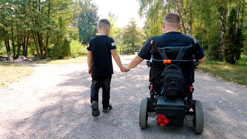 father's day. person with a disability. dad and his little cute son are walking in park, on summer day. dad is a wheelchair user. people with special needs. Royalty-Free Stock Footage #1085806769