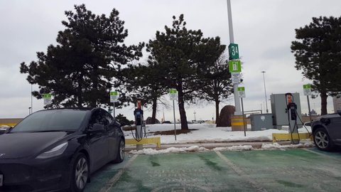 Toronto, Ontario, Canada - January 22nd, 2022. Driver Point of View Driving Up To EV Electric Vehicle Charging Station in Winter. Drive Car Vehicle Toward EV Recharge Parking Spot.