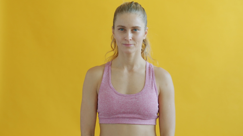 Portrait of joyful sports lady in trendy outfit smelling chololate then eating and smiling on yellow background. Unhealthy food and youth concept.