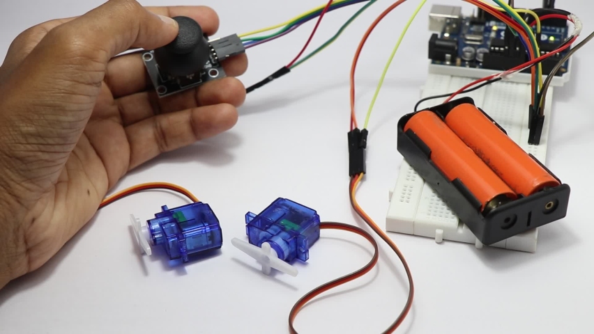 Thumb joystick module controlling the micro servos in a prototype electronic circuit showing some testing by a young inventor in laboratory Royalty-Free Stock Footage #1085821406