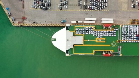 Aerial drone top down pan video of large car carrier ro ro vessel anchored in car terminal of Mediterranean port