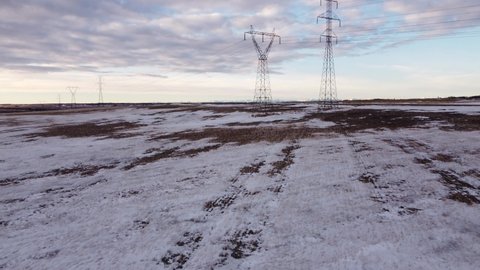 Aerial tilt reveal of transmission lines and power line towers on the Alberta Prairies in Canada.