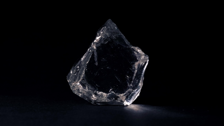 Rough diamond. Transparent stone. A piece of ice. Black background.