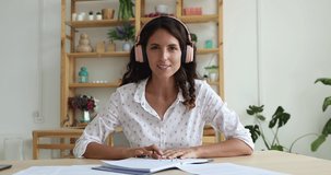 Businesswoman wear headphones sit at desk looks at camera talk to colleague discuss papers, do paperwork use video conferencing. Solve business on quarantine, self-distancing, videocall event concept