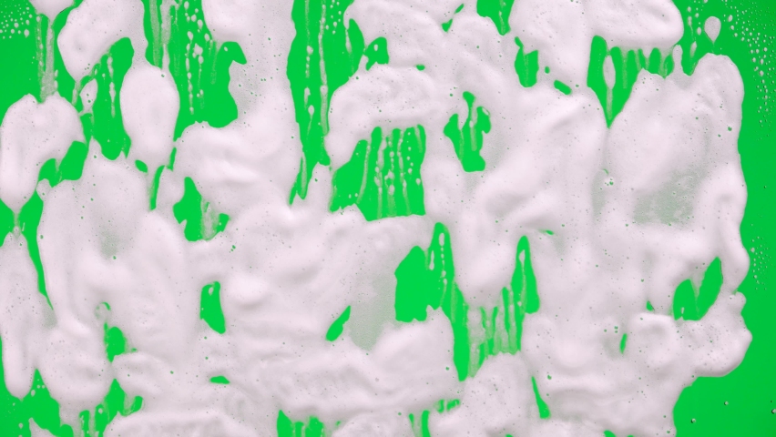 White soap suds flowing down window glass on green screen chroma key background. Cleaning windows with cleaning disinfectant. Hygiene, disinfection, housework, household, cleanup, washing. Close up. | Shutterstock HD Video #1085846054