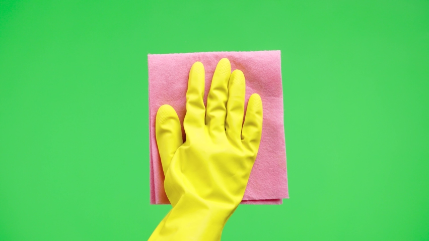 Woman's hand in yellow rubber gloves wipes window glass with dry rag against the background of green screen chroma key. Housewife does housework. Cleaning transparent shiny glass from dust. Close up. | Shutterstock HD Video #1085846057