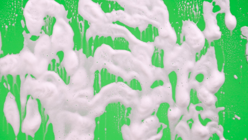 Woman's hand in rubber yellow glove washes window on green screen chroma key background. Housekeeper wipes soap suds from the glass. Cleaning windows with cleaning disinfectant. Close up. | Shutterstock HD Video #1085846060