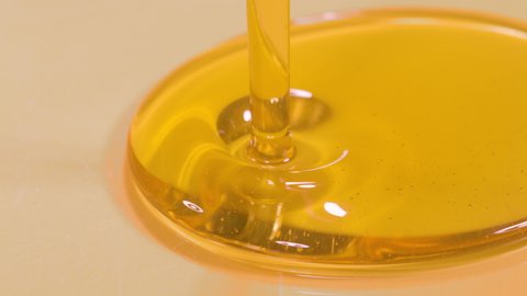 SLOW MOTION, MACRO, DOF: Delicious organic extra virgin olive oil flows into a deep dish. Shot of unrefined cold pressed walnut oil getting poured into a large container. Natural beauty product.