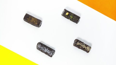 4k Rectangular chocolate candies on a white background with yellow and orange accents. Sweet dessert concept. Stop motion animation. Copy space. Flat lay.