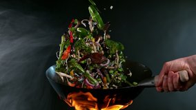 Super Slow Motion Shot of Wok Pan with Flying Ingredients in the Air and Fire Flames. Filmed on High Speed Cinema Camera at 1000 FPS. - Powered by Shutterstock - Get 15% off with code: PIKWIZARD15