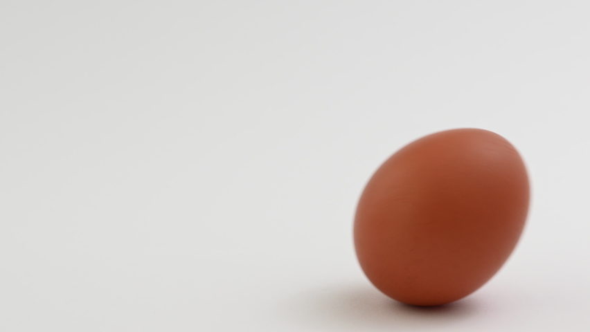 4K video of rolling broun organic egg on white background