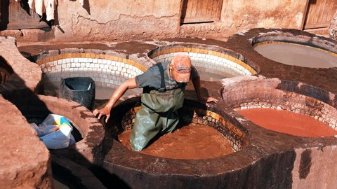 Fes, Morocco. October 10, 2021. Leather dying in a traditional tannery in the city Fes, Morocco. The Fez dye works. Leather dressing according to ancient technologies.