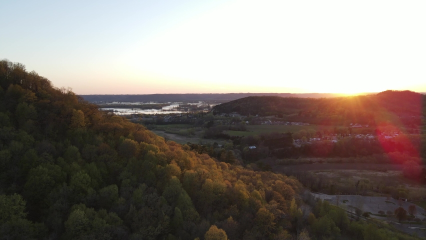 Gorgeous aerial view at sunset of valley over farm fields, homes, and looking toward the Mississippi river. Autumn colors developing in the forest. 