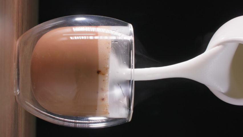 Cappuccinos, delicious aromatic coffee drink pours milk foam from a milk jug in a transparent glass, vertical | Shutterstock HD Video #1085852249