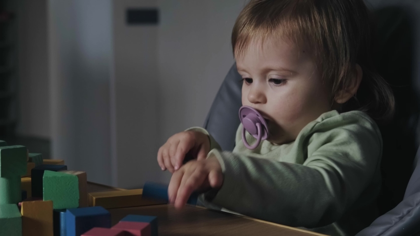Video with a baby girl sitting at the table in the baby room playing with colors educational toys. For game design.
