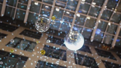 Two mirrored disco balls are suspended from the ceiling inside a high-rise building.