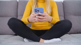 Young woman using mobile phone for online communication. White female typing message on social media app in modern smartphone gadget. Person texting on messenger application white sitting on couch