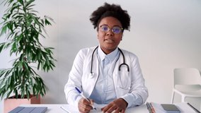 Doctor physician having online video call or virtual conference meeting speaks to camera. African american physician making online consultation to patient. Head shot portrait nurse woman at desk