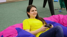 A woman plays a game console, holds a joystick in her hands and smiles.