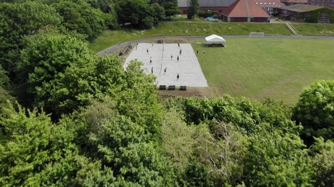 Aerial: drone shot of beach volley among lush landscape with green trees while people are playing beach volley in the sand