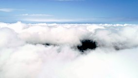 Drone shot flying through amazingly beautiful cloudscape. Picturesque view of white fluffy cloudsing softly on the clear blue sky.