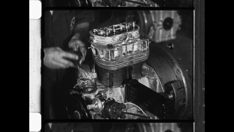 1950 Wolfsburg, Germany. Volkswagen automobile factory.  Factory workers assemble four stroke engines. Close Up of gear box, pistons, carburetor and cylinder head.  4K Overscan of Archival Newsreel