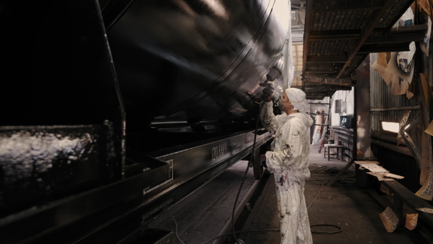 The Hard working professional is using the spray painting tool at the Manufacturing Facility. The hard working professional is coloring the rail wagon. A hard working professional in a dirty uniform. Royalty-Free Stock Footage #1085885363