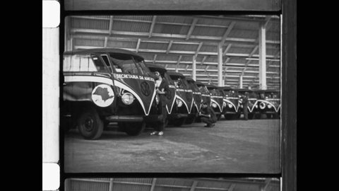 1959 Anchieta, Espírito Santo.  Factory workers assemble Volkswagen Type 2, or VW Bus at the Volkswagen automobile factory. Worker head carrying car part. 4K Overscan of Archival 16mm Newsreel