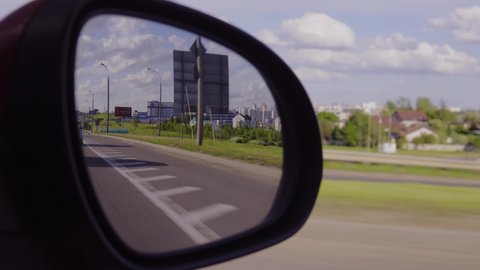 Red automobile in motion. View in the rear view side mirror of a auto, driving a red car along the track	
