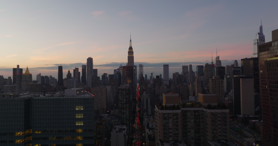 Panoramic view of high rise buildings in midtown. Illuminated top of Empire State Building against sky at dusk. Manhattan, New York City, USA Royalty-Free Stock Footage #1085886725