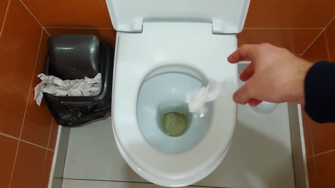 Man throws and flushes toilet paper in the toilet, close-up