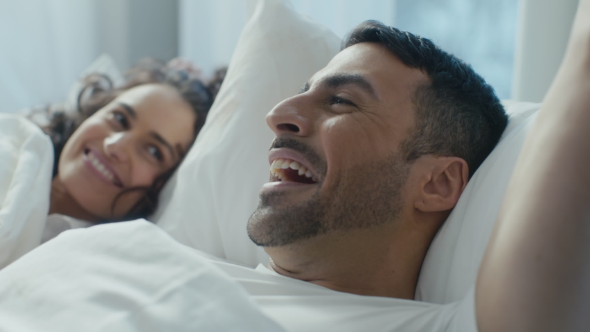Close Up Shot of a Beautiful Young Ethnic Couple Laying in Bed on a Sunday Morning, Talking About Their Day As They Cuddle Together, Celebrating Valentines Day With a Day Off in a Fancy Hotel. Royalty-Free Stock Footage #1085890472