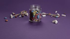 Colored mixed candies closeup. Jar falls. Dragee crumbles. Sweet packshot. Purple pack shot background - Powered by Shutterstock - Get 15% off with code: PIKWIZARD15