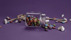 Colorful mixed candies in glass jar. Dragee drop. Sweet packshot. Purple pack shot background FullHD - Powered by Shutterstock - Get 15% off with code: PIKWIZARD15