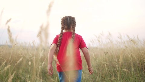 little girl running across the field in nature in the park. happy family kid dream concept. little girl running in dry grass in wild park. free girl happy childhood and family fun concept