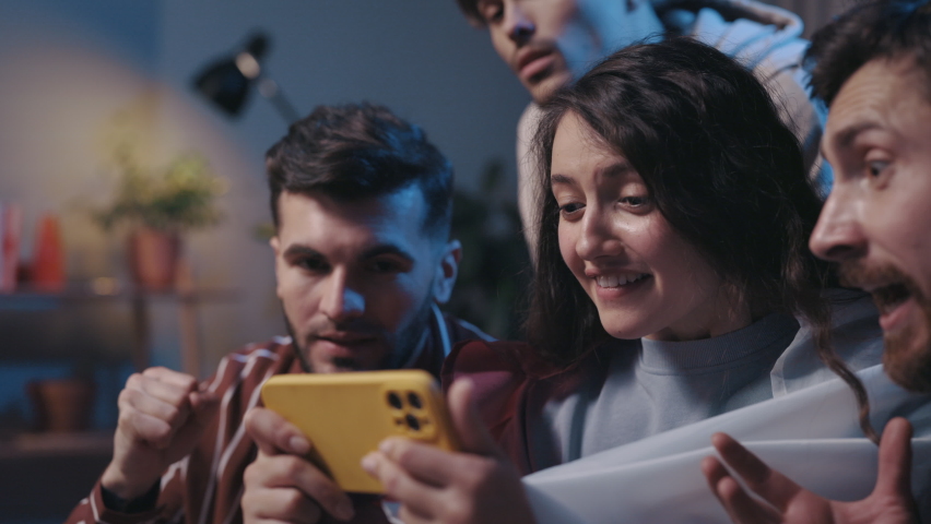 Positive cheerful people looking at the smartphone with happy emotions during football game. Excited football fans using modern smartphone on at home. Football fans concept | Shutterstock HD Video #1085896340
