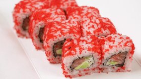 Close-up view 4k video footage of tasty fresh sushi roll California with salmon isolated on white paper food tray background