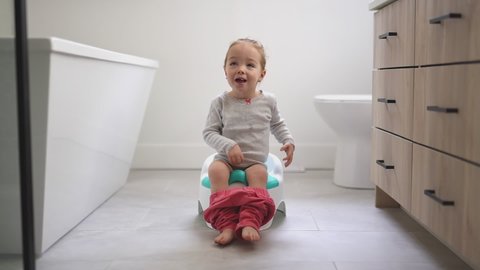 An Adorable young baby child sitting and learning how to use the toilet 