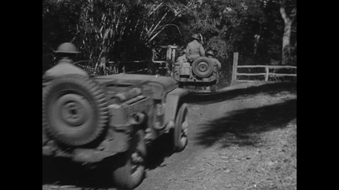 CIRCA 1940s - American soldiers drive jeeps through a forest.