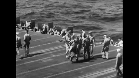 CIRCA 1944 - A US Navy plane that crashed on an aircraft carrier is towed across the deck, and sailors help the pilot walk away.