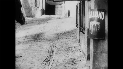 CIRCA 1915 - In this silent comedy, a man (Charlie Chaplin) walks down a sidewalk in Spain while a horse-drawn buggy drives by.