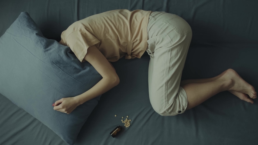 A young woman lies on the bed with her head under the pillow. Concept of depression or mental health problems. Royalty-Free Stock Footage #1085906726