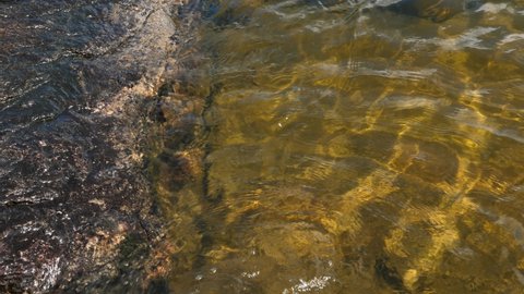 Clear lake water lapping against granite rock. Muskoka, Ontario, Canada.