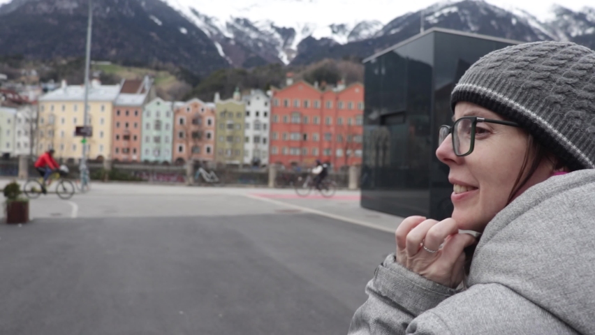 Woman walking in Innsbruck, Austria and visiting the beautiful Capital of Tirol. Europe winter landscape with view of the alps mountains and the colorful houses and buildings of the city.