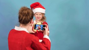Cheerful mother holding phone make little preschool age girl. mom use gadget have fun take portrait spend time together at home Shoot blog for Christmas. child on phone camera. online call to pandemic