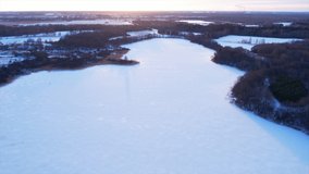 Aerial view of a frozen lake in the forest during the winter season. Snow-covered lake on a frosty day against the backdrop of sunlight. Drone flight over lake in winter season with snow and ice. - Powered by Shutterstock - Get 15% off with code: PIKWIZARD15