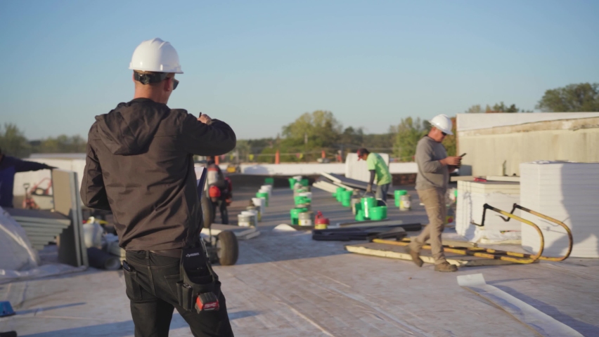 Project manager wearing a construction hat supervising a flat roof installation on a sunny day Royalty-Free Stock Footage #1085915099