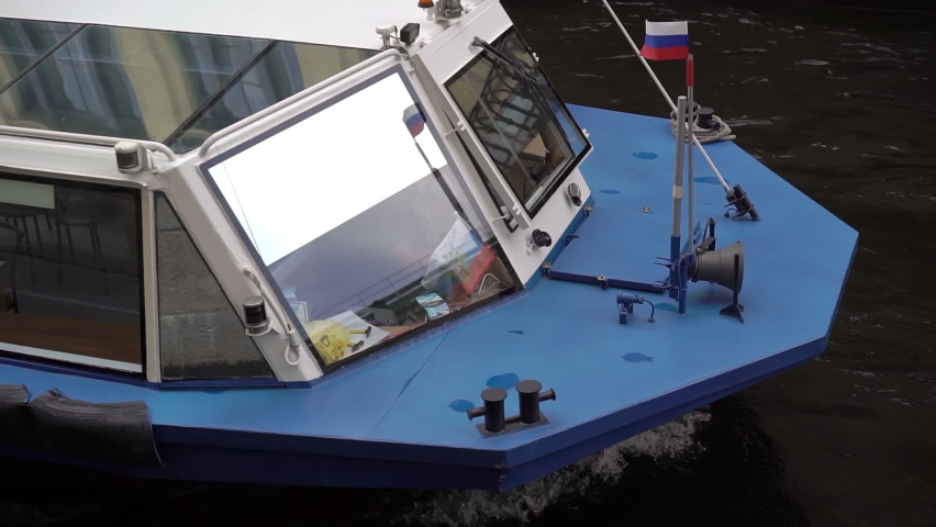 Sailing passenger touristic ship in a city. River tour in Saint-Petersburg, Russia historical center, river Neva. Embankment in town, cloudy weather in summer season. Motor boat or yacht sail.