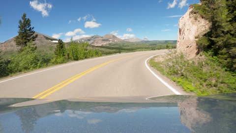 Driving a car going up on asphalt curvy mountain road in Montana. Blue sky, sunny day	