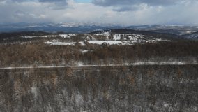 Travel journey transport and vacation concept High angle aerial side view drone video on the road car driving in mountain range with white snow in winter day near Knjazevac in Serbia
